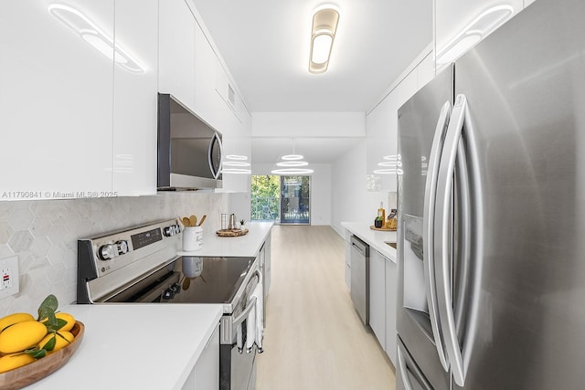 kitchen featuring white cabinets, appliances with stainless steel finishes, light countertops, light wood-style flooring, and tasteful backsplash