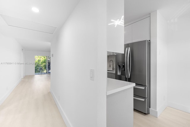 hallway with a sink, baseboards, recessed lighting, and light wood-style flooring