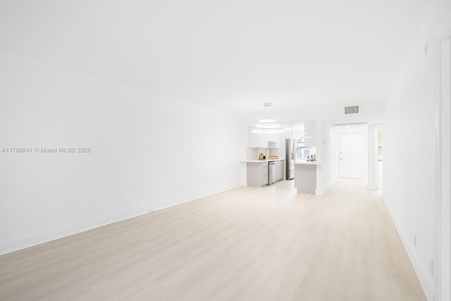 unfurnished living room featuring baseboards, light wood-style flooring, and visible vents