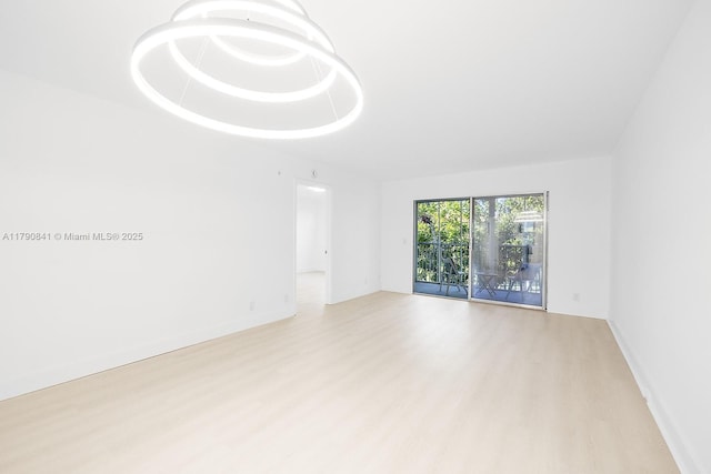 spare room featuring baseboards and light wood finished floors