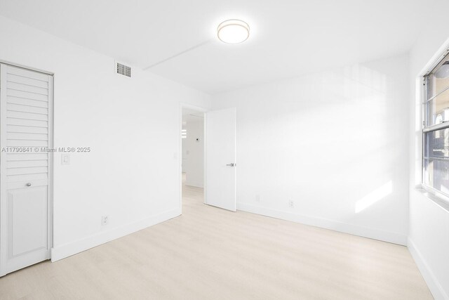 unfurnished bedroom featuring baseboards, visible vents, and wood finished floors