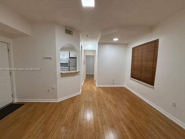 spare room featuring baseboards, visible vents, and hardwood / wood-style floors