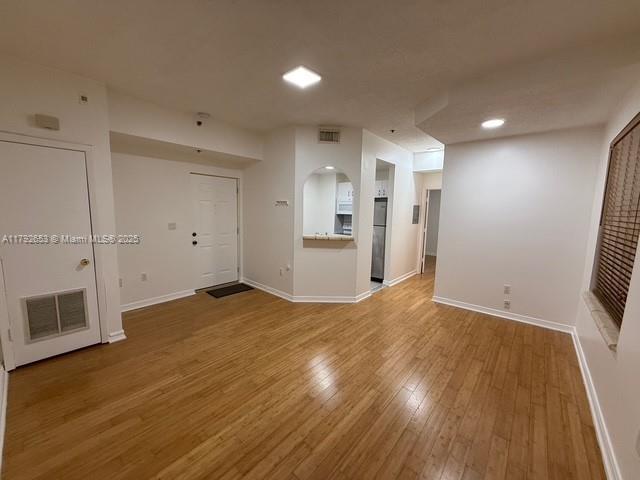 unfurnished room featuring baseboards, visible vents, and hardwood / wood-style floors