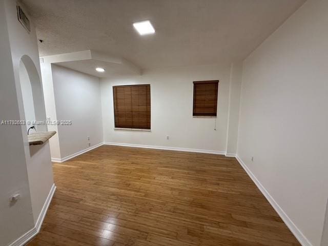 unfurnished room featuring visible vents, baseboards, and wood finished floors