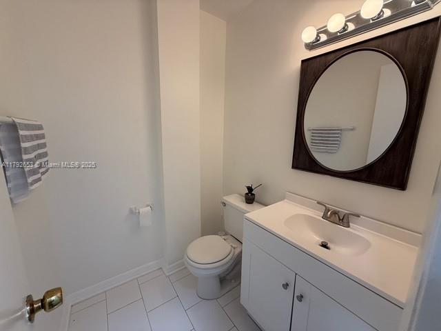 bathroom featuring vanity, tile patterned flooring, baseboards, and toilet