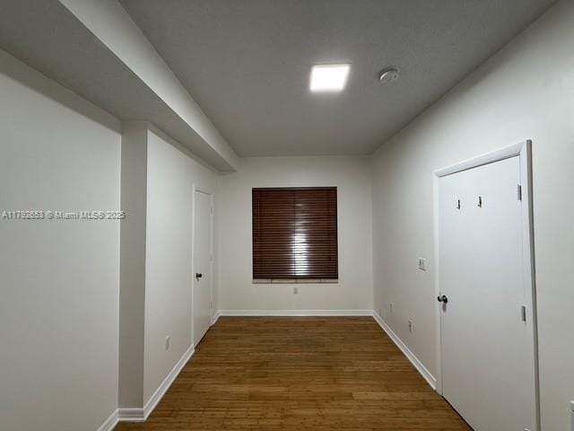 corridor featuring baseboards and wood finished floors