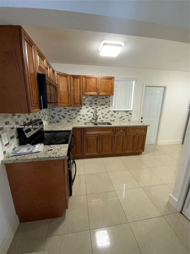 kitchen featuring a sink, brown cabinets, tasteful backsplash, and electric range