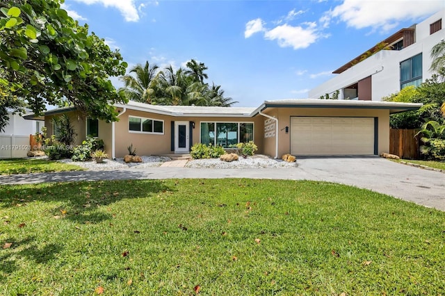 view of front facade featuring fence, a front lawn, concrete driveway, an attached garage, and stucco siding