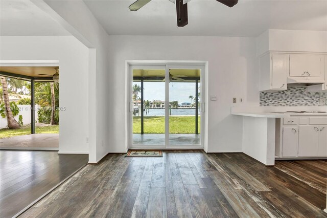 unfurnished dining area with a water view, a ceiling fan, and dark wood-type flooring