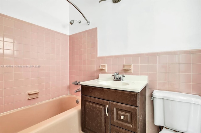 full bathroom featuring vanity, washtub / shower combination, toilet, and tile walls