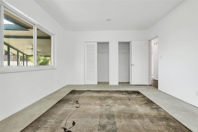 unfurnished bedroom featuring two closets and carpet flooring