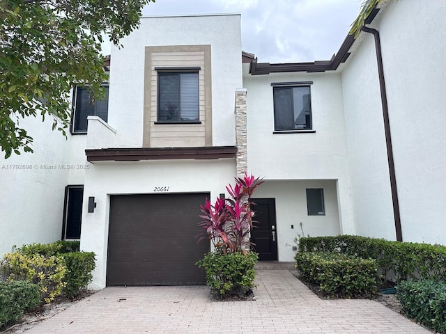 view of front of home featuring an attached garage, decorative driveway, and stucco siding
