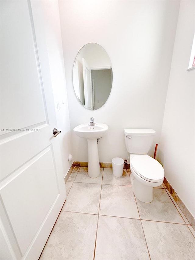 half bathroom featuring baseboards, tile patterned floors, and toilet