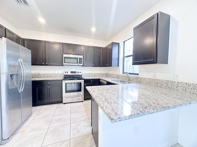 kitchen with dark brown cabinetry, appliances with stainless steel finishes, a sink, a peninsula, and visible vents
