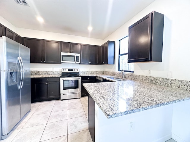 kitchen with visible vents, appliances with stainless steel finishes, light stone countertops, a sink, and a peninsula