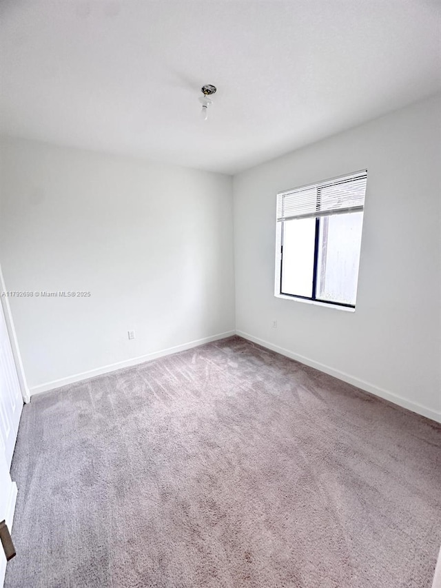 spare room with baseboards and carpet flooring
