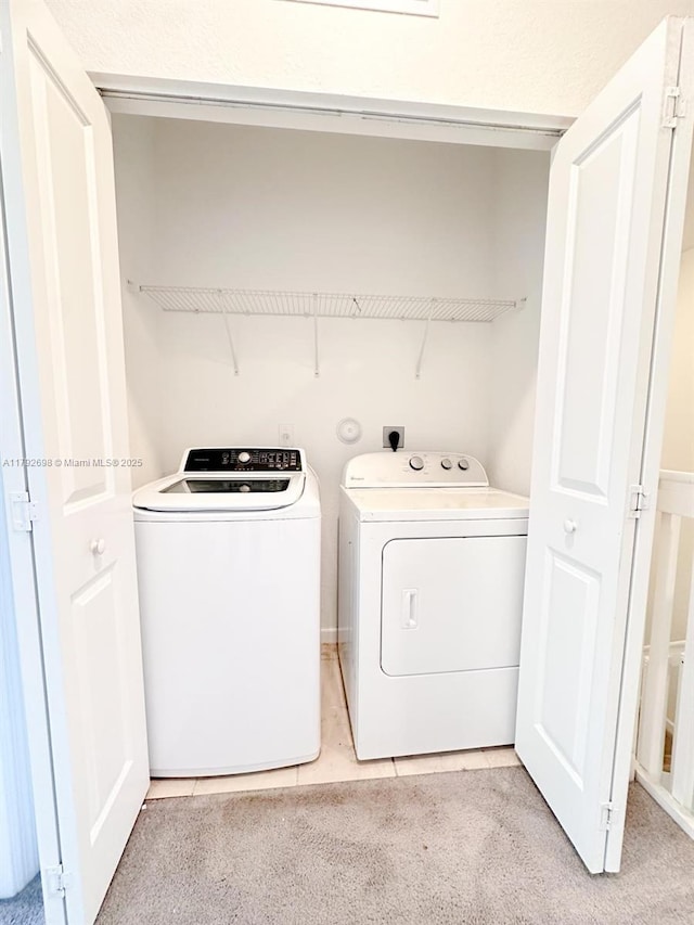 washroom featuring washing machine and clothes dryer, laundry area, and light carpet
