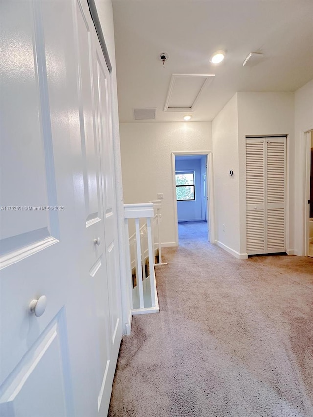hallway featuring attic access, carpet, baseboards, an upstairs landing, and visible vents