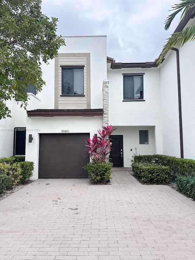 view of front of home featuring an attached garage, decorative driveway, and stucco siding