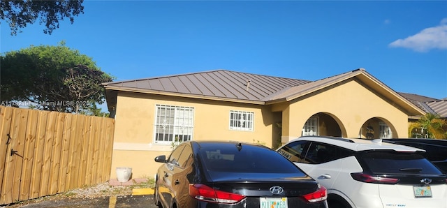 view of front of home featuring uncovered parking, stucco siding, metal roof, and a standing seam roof