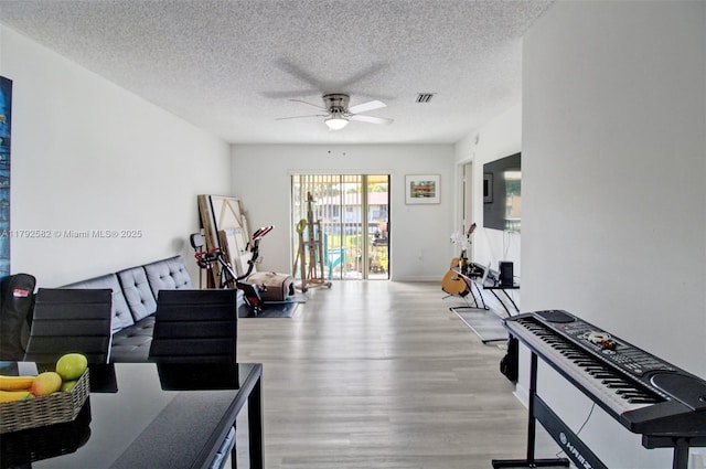 interior space with visible vents, a ceiling fan, a textured ceiling, and wood finished floors