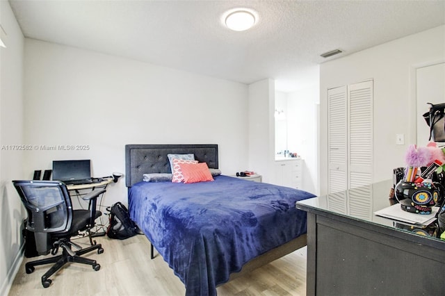 bedroom with visible vents, wood finished floors, and a closet