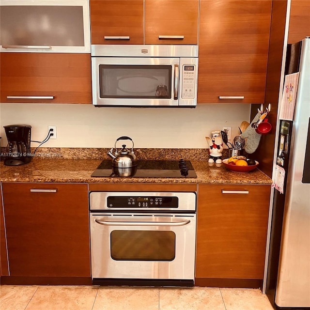 kitchen featuring dark stone counters, stainless steel appliances, and light tile patterned floors