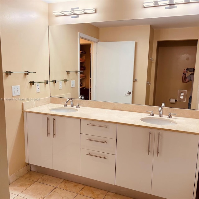 full bath with double vanity, a sink, and baseboards
