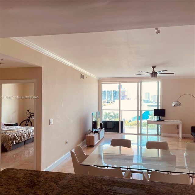 interior space featuring visible vents, ornamental molding, a wall of windows, baseboards, and ceiling fan