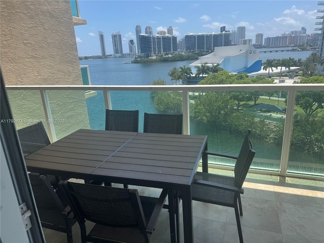 balcony with a view of city, a water view, and outdoor dining area