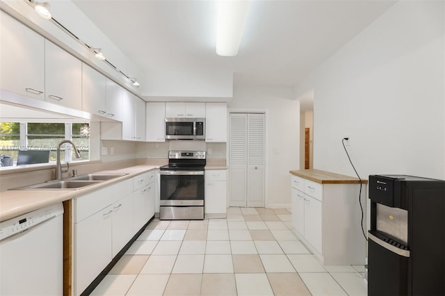 7920 SW 132nd St, Pinecrest, FL 33156 - kitchen with backsplash, appliances with stainless steel finishes, a sink, light countertops, and white cabinetry