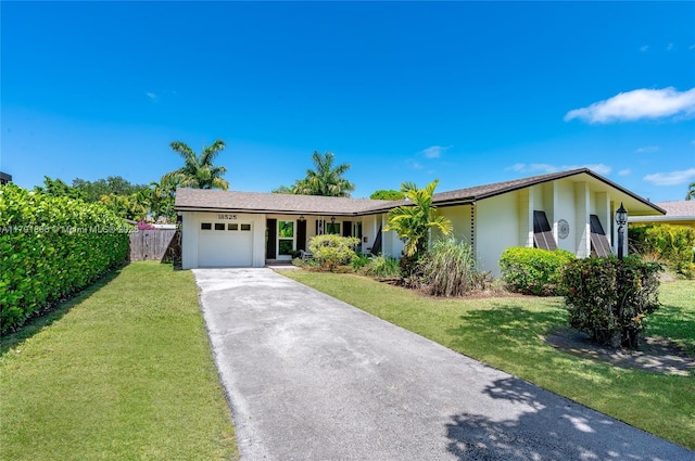ranch-style house with concrete driveway, fence, a front yard, and a garage