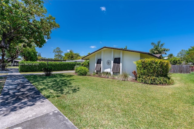 view of front of property with fence, stucco siding, and a front yard