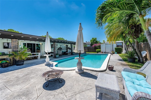 view of pool featuring a fenced backyard, a shed, a fenced in pool, a patio area, and an outdoor fire pit
