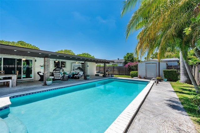 view of pool with an outdoor living space, a fenced backyard, ceiling fan, and a storage shed