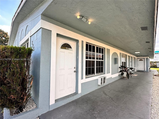 property entrance with a porch and stucco siding