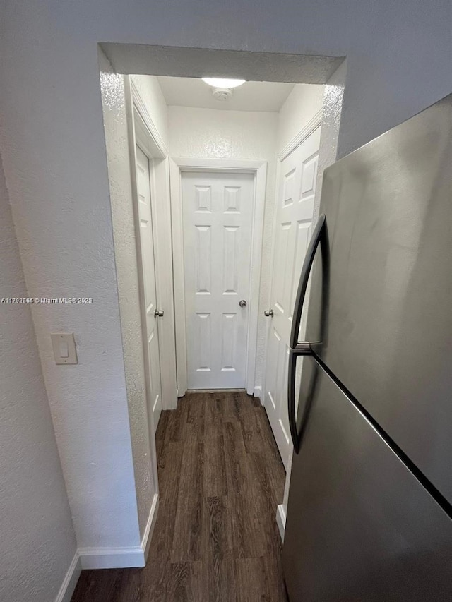 hallway with baseboards, a textured wall, and dark wood-style floors