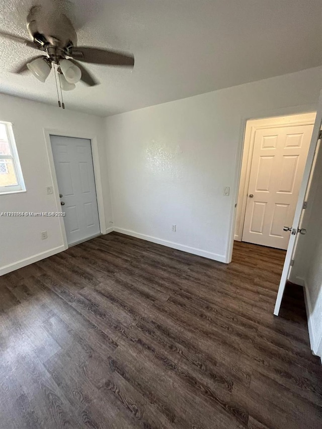 interior space with baseboards, a ceiling fan, and dark wood-style flooring