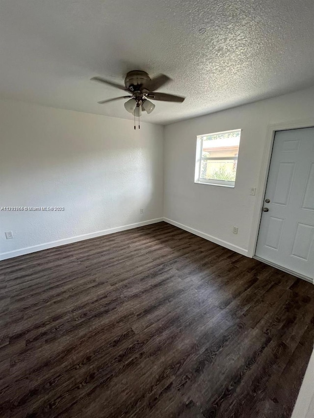 spare room featuring baseboards, ceiling fan, a textured ceiling, and dark wood-type flooring