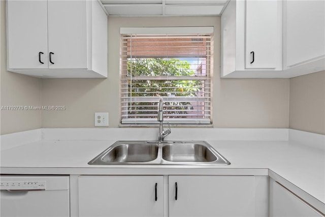 kitchen featuring light countertops, white dishwasher, white cabinets, and a sink