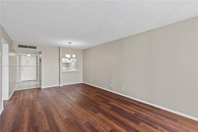 interior space featuring a textured ceiling, visible vents, baseboards, a chandelier, and dark wood-type flooring