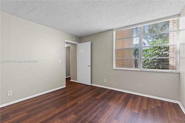 unfurnished room with baseboards, a textured ceiling, and wood finished floors
