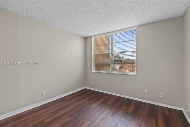 unfurnished room with a textured ceiling, baseboards, and dark wood-type flooring