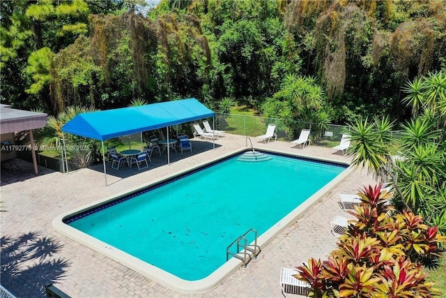 community pool with a patio and fence