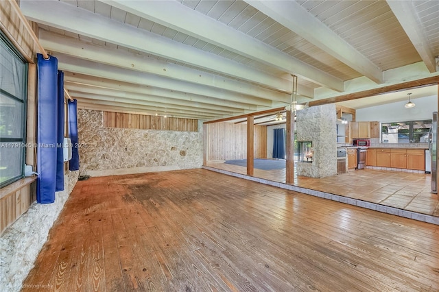 unfurnished living room with beamed ceiling and hardwood / wood-style floors