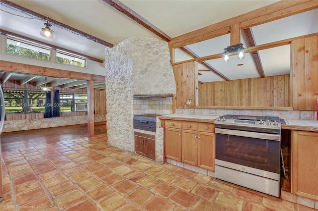kitchen with wood walls, stainless steel gas stove, open floor plan, tile countertops, and lofted ceiling with beams