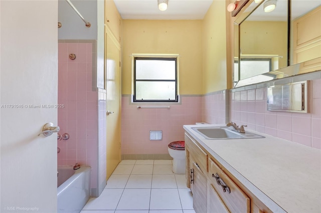 full bath featuring tile walls, tile patterned flooring, wainscoting, toilet, and washtub / shower combination