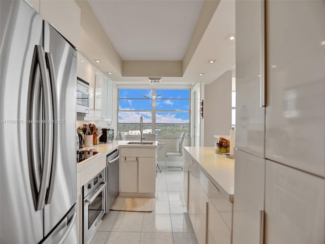 kitchen featuring light tile patterned flooring, appliances with stainless steel finishes, a sink, light countertops, and modern cabinets