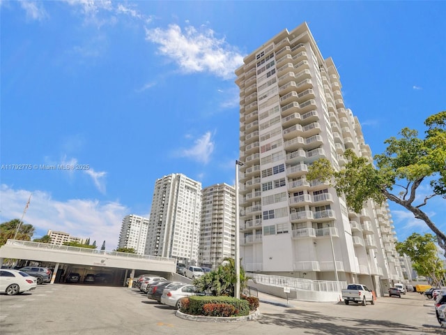 view of building exterior featuring covered and uncovered parking and a city view