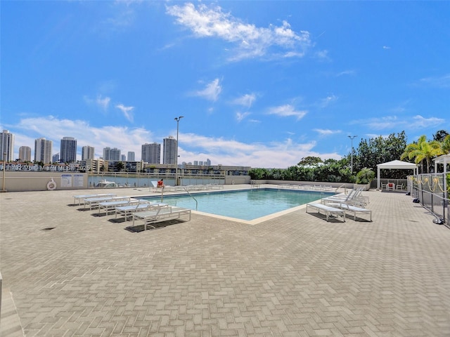 pool with a gazebo, a patio area, fence, and a city view